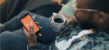 Person having coffee while banking on their phone.