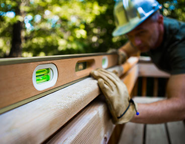 Carpenter leveling a rail on a new deck build.