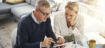 Couple looking a tablet having coffee.