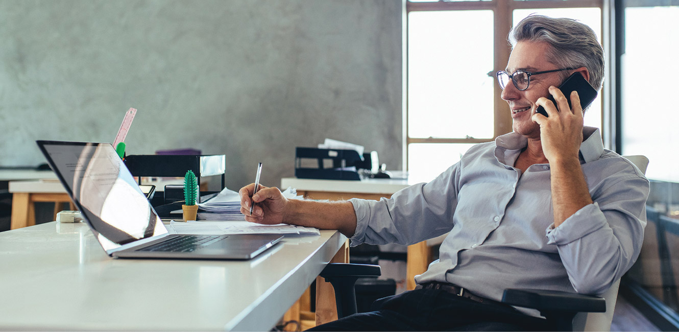 Business man on the phone in front of laptop.