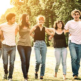 Group of young people walking arm in arm.